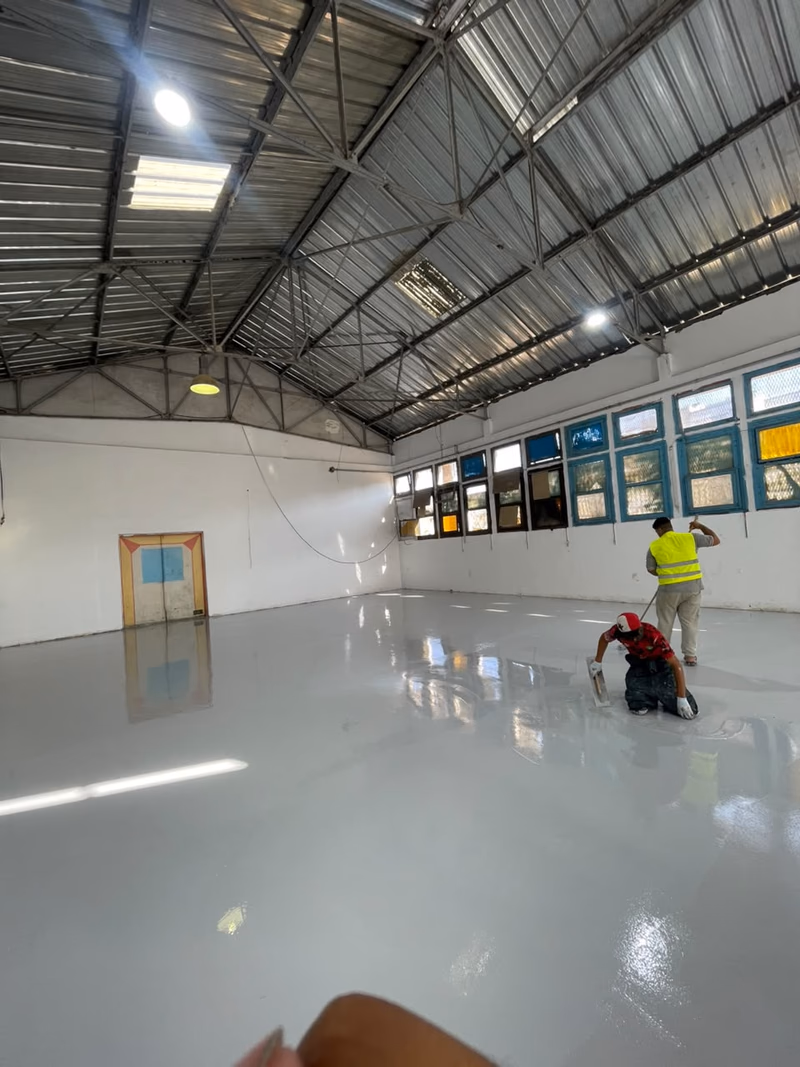 Équipe Sol Epoxy appliquant une résine époxy grise dans une grande salle