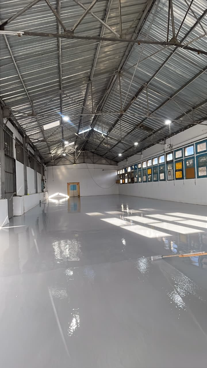 Grande salle au sol époxy gris brillant où se reflète la lumière du jour