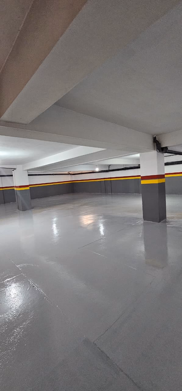 Parking en sous-sol au sol époxy, poteau peint en gris, rouge et jaune